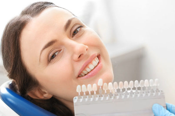 Woman with shade guide by her teeth